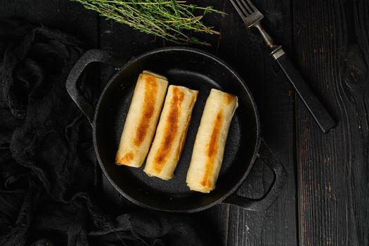 Fried georgian crepes stuffed with suluguni, on black wooden table background, top view flat lay, with copy space for text