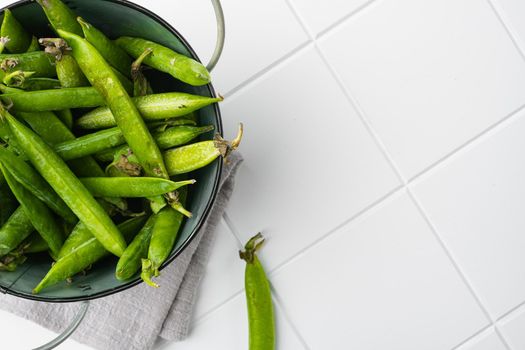 Fresh picked green pea, on white ceramic squared tile table background, top view flat lay, with copy space for text