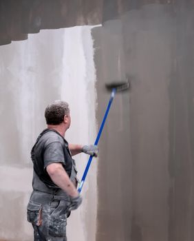 man painting wall with roller. worker paint a house wall. renovation concept