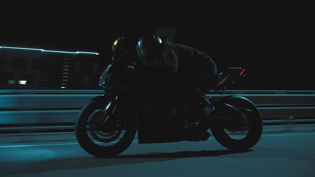 A man rides a sports motorcycle through the city at night in 4k