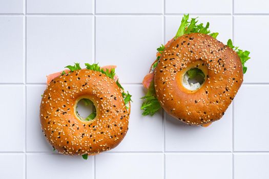 Bagel and lox set, on white ceramic squared tile table background, top view flat lay, with copy space for text