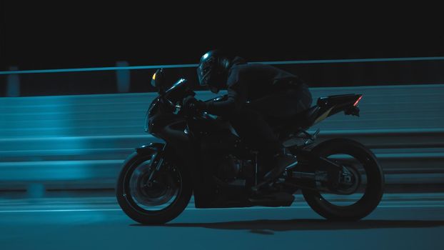 A man rides a sports motorcycle through the city at night in 4k