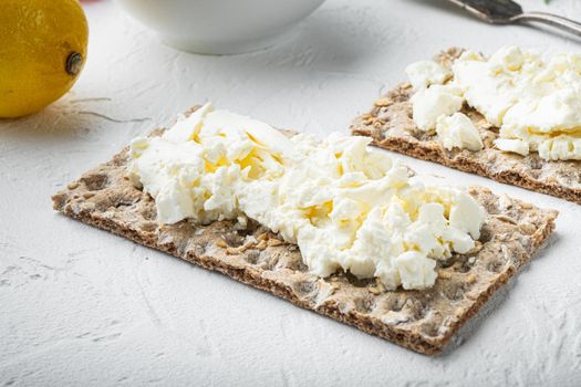 Fresh rye crispbreads with cream cheese set, on white stone table background, with copy space for text