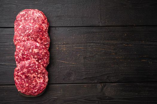 Patty of minced meat for burger set, on black wooden table background, top view flat lay, with copy space for text