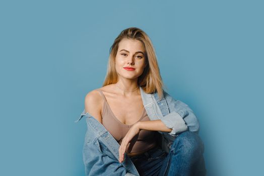 Attractive woman in casual clothes. Fashionable woman-model posing on the chair, studio photography.