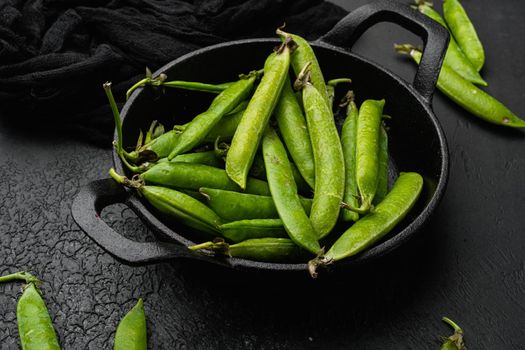 Raw Green Organic Snow Peas, on black dark stone table background