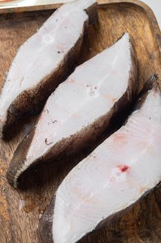 Chilled halibut steaks set, with ingredients and rosemary herbs, on white stone table background