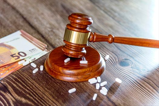 Judges hammer, Euro Notes, syringe and vaccine bottle on a wooden background. Concept for a medical judgment