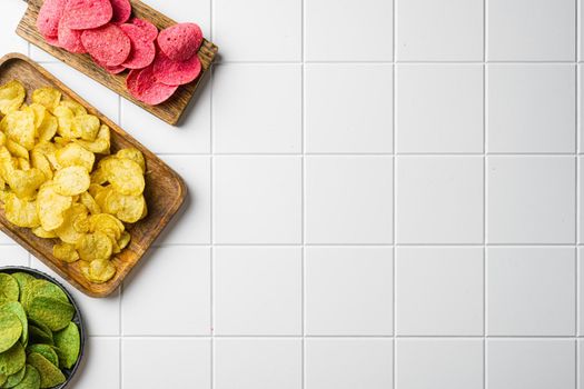 Variation different potato chips, on white ceramic squared tile table background, top view flat lay, with copy space for text