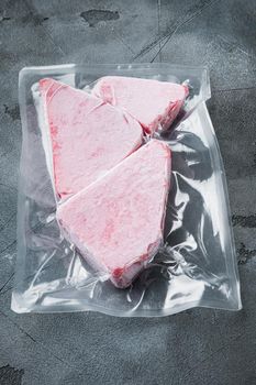 Frozen Tuna fish steak in a vacuum plastic package set, on gray stone background