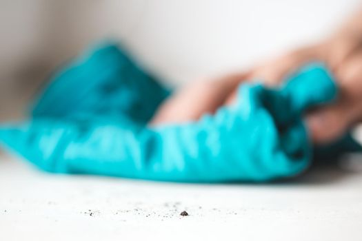 Male hand without gloves rubs dust from the windowsill. Mopping with a blue cloth. Housekeeping concept. Selective Focus on the dust