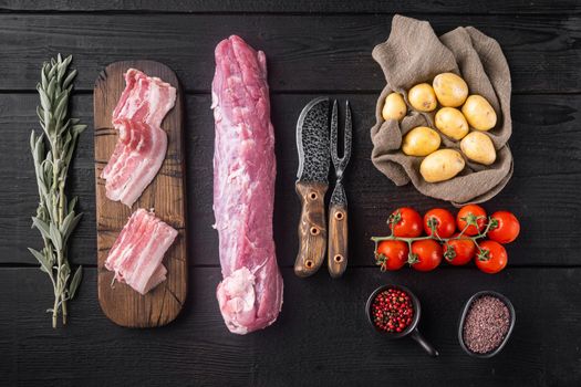 Raw pork tenderloin with ingredients and herbs set, on black wooden table background, top view flat lay