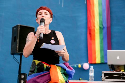 Santa Pola, Alicante, Spain- July 2, 2022: Lesbian woman giving the proclamation speech at the Gay Pride Parade with rainbow flag