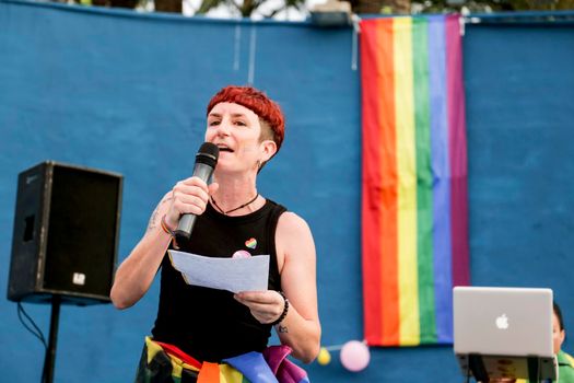 Santa Pola, Alicante, Spain- July 2, 2022: Lesbian woman giving the proclamation speech at the Gay Pride Parade with rainbow flag