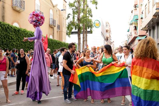 Santa Pola, Alicante, Spain- July 2, 2022: Spanish People attending Gay Pride Parade with rainbow flags, banners and colorful costumes