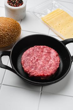 Raw BBQ Beef Burger Cutlets, on white ceramic squared tile table background