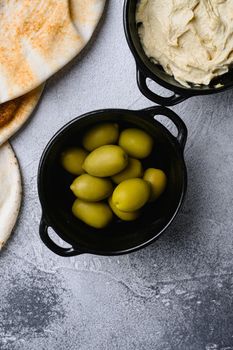 Green olives in oil, on gray stone table background, top view flat lay, with copy space for text