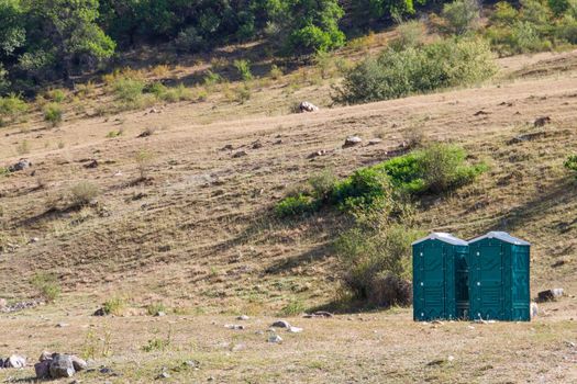 Two blue plastic cabins of dry closets in a natural park, copy space.
