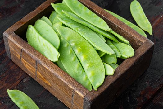 Fresh organic mangetout, also known as sugar snap pea set, in wooden box, on old dark wooden table background