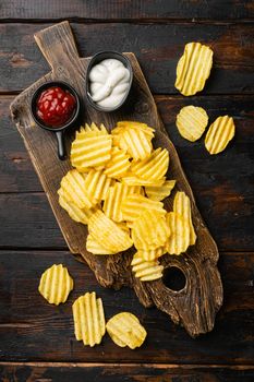 Wavy Potato Chips, on old dark wooden table background, top view flat lay