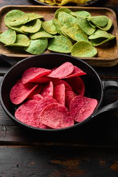 Potato chips pink colored, on old dark wooden table background