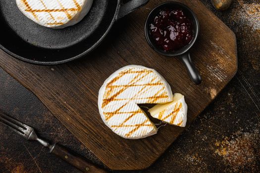 Grilled camembert or brie cheese, on old dark rustic table background, top view flat lay