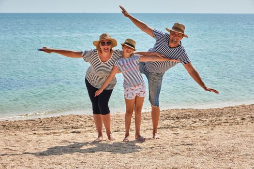 Happy family on the beach. People having fun on summer vacation. Father, mother and child against blue sea background. Holiday travel concept