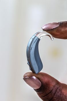 Close-up hearing prosthesis held on a light background