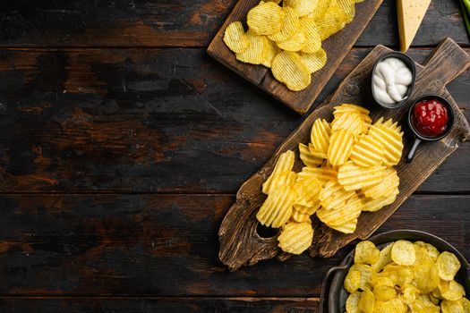 Cheddar Sour Cream Flavored Potato Chips, on old dark wooden table background, top view flat lay, with copy space for text