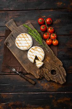 Grilled camembert or brie cheese, on old dark wooden table background, top view flat lay, with copy space for text