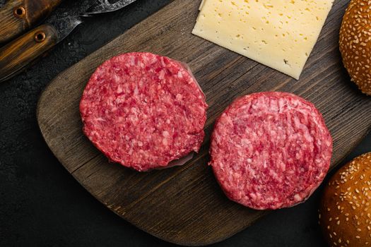 Fresh raw minced homemade farmers grill beef burgers, on black dark stone table background, top view flat lay