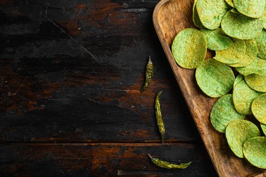 Green potato chips, on old dark wooden table background, top view flat lay, with copy space for text