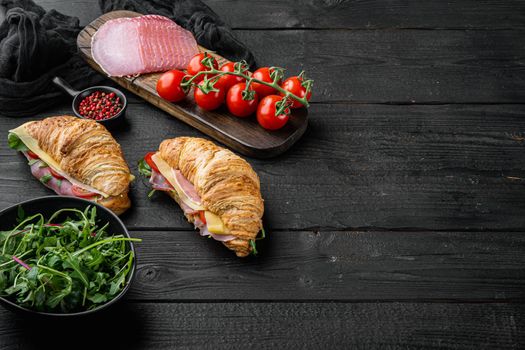 Classic BLT croissant sandwiches set, with herbs and ingredients, on black wooden table background, with copy space for text
