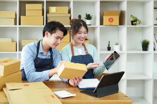 Portrait of a small start-up and SME owner, an Asian male and female entrepreneur checking orders and packing for customers, self-employed, freelance, online selling.