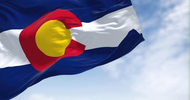 the flag of the US state of Colorado waving in the wind. Colorado is a state in the Mountain West subregion of the Western United States