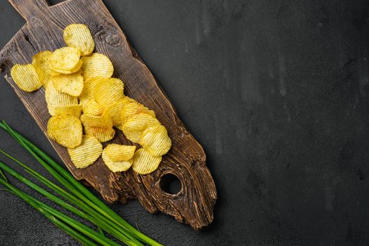 Wavy Ranch Flavored Potato Chips, on black dark stone table background, top view flat lay, with copy space for text