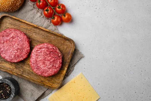 Organic raw ground beef, round patties for making homemade burger, on gray stone table background, top view flat lay, with copy space for text