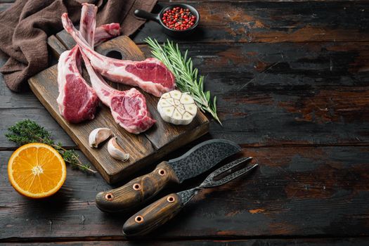 Fresh raw butchers lamb beef cutlets set, with ingredients carrot orange, herbs, on old dark wooden table background , with copyspace and space for text