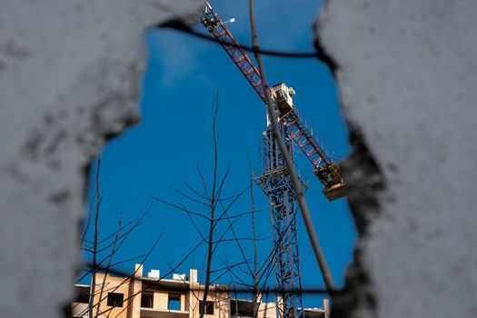 Crane, construction site. Crane and building under construction with blue sky from old damaged house