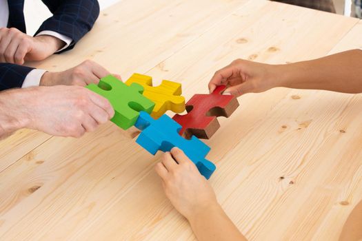 Business people helping in assembling puzzle, cooperation in decision making, team support in solving problems and corporate group teamwork concept, connecting pieces