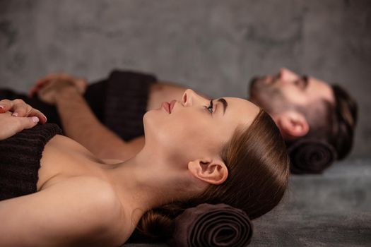 Young man and woman lying down on massage beds at luxury spa and wellness center