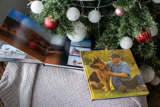 Photo book family photo album under the Christmas tree surrounded by Christmas gifts.