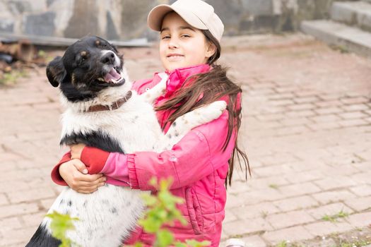 little girl is hugging dog outdoors