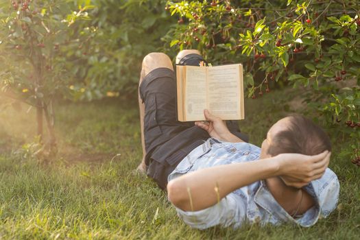 Man reading a book on the grass.