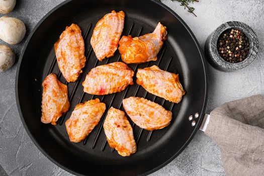 Fresh chicken wings with spices and the sauce set, on gray stone table background, top view flat lay