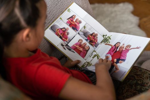 a little girl looking at a photo album in the living room.