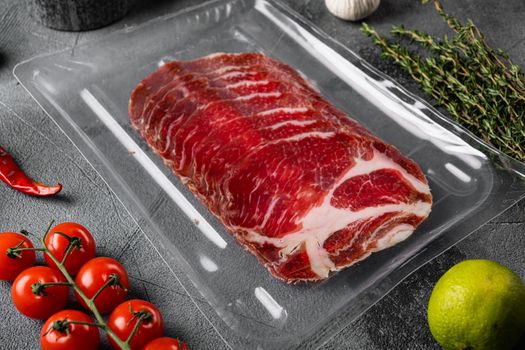 Vacuum packed cured coppa ham set, on gray stone table background