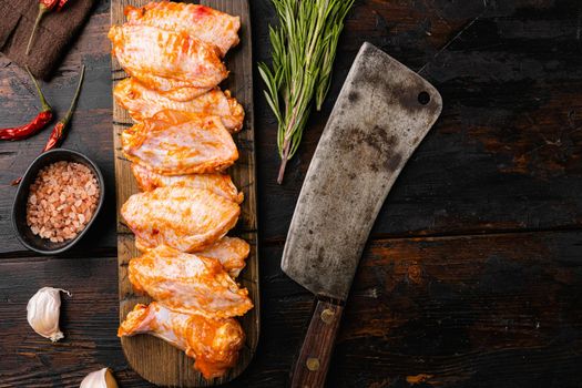 Raw marinated chicken wings with spices set, on old dark wooden table background, top view flat lay, with copy space for text