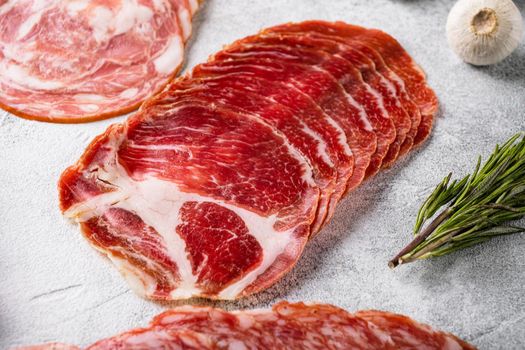 Italian sliced cured coppa meat set, on gray stone table background