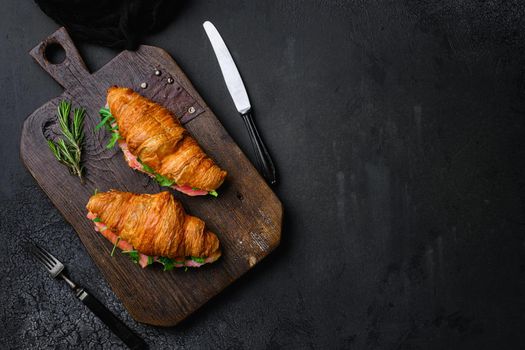 Croissant sandwich with salted salmon set, on black dark stone table background, top view flat lay, with copy space for text